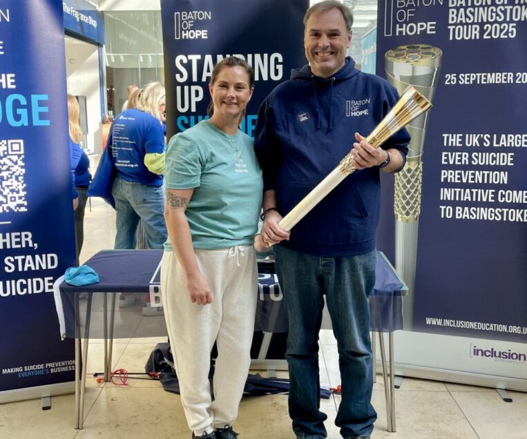 A woman and a man stood next to each other, with the man holding an elaborate metal baton in his hands.