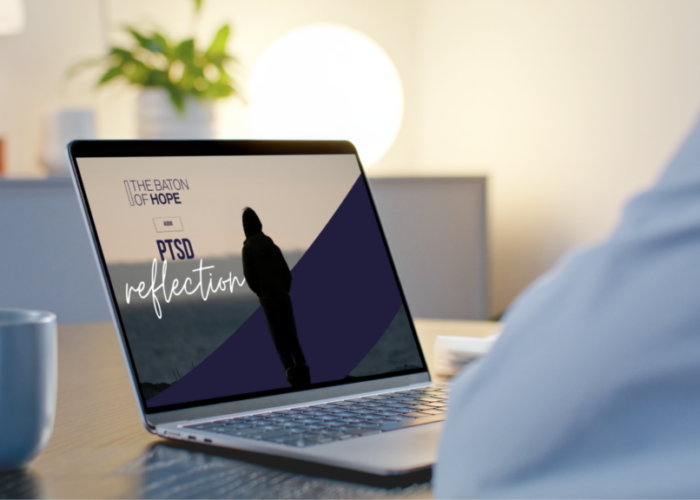 A mockup design showing a man looking at a laptop screen, which shows the silhouette of a woman from behind with the text "The Baton of Hope Audio PTSD Reflection" on the image.